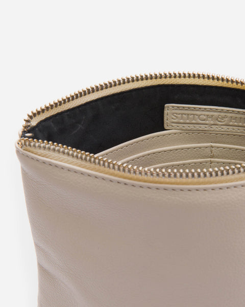 Off white leather clutch with a wrist strap.